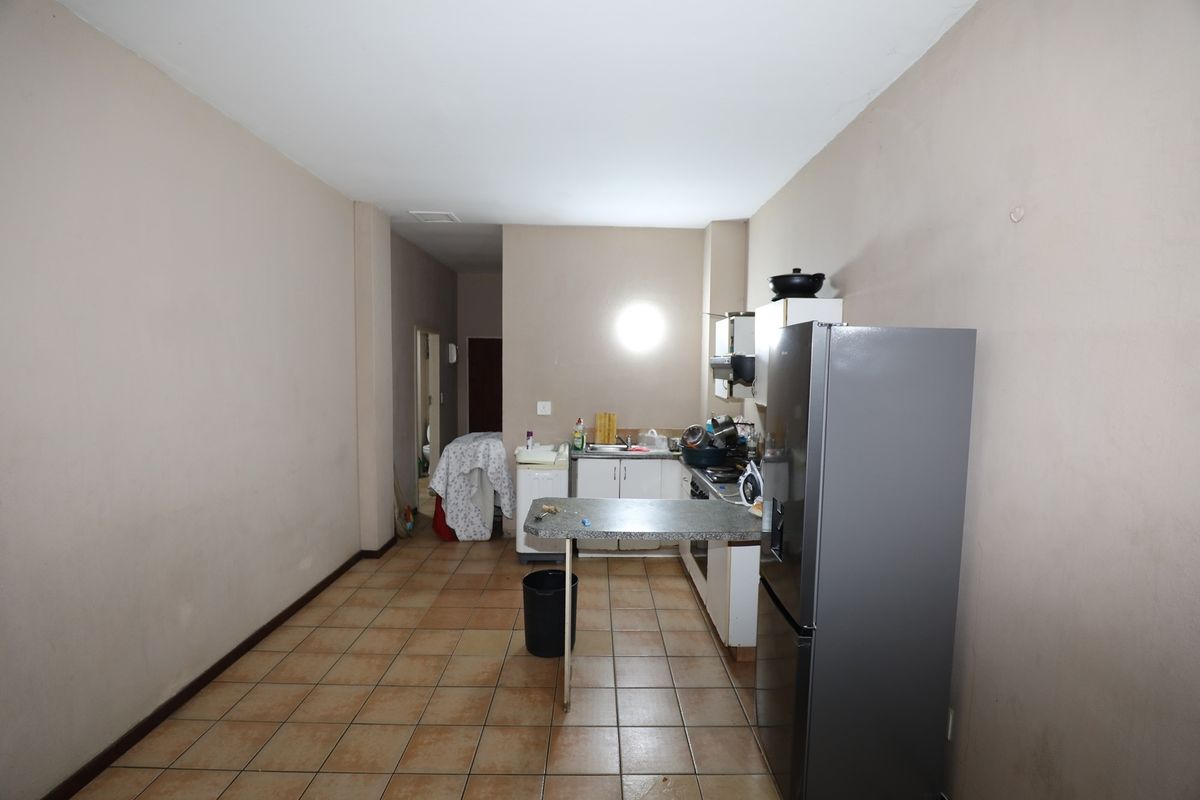 A functional kitchen area featuring tiled flooring, built-in cabinetry, and a breakfast counter, offering a practical layout for daily meal preparation.