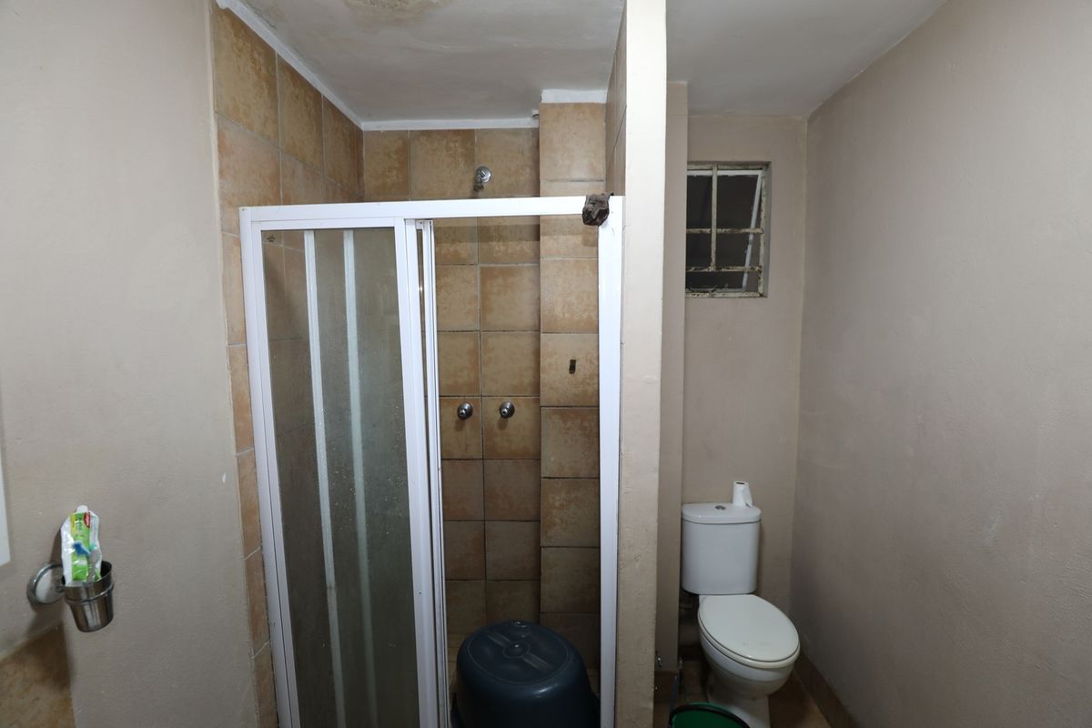A functional bathroom featuring a tiled shower enclosure with a glass door and a standard white toilet.