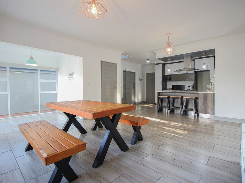 Spacious open-plan living and dining area featuring modern tiled flooring, a contemporary kitchen with an island, and direct access to the patio.