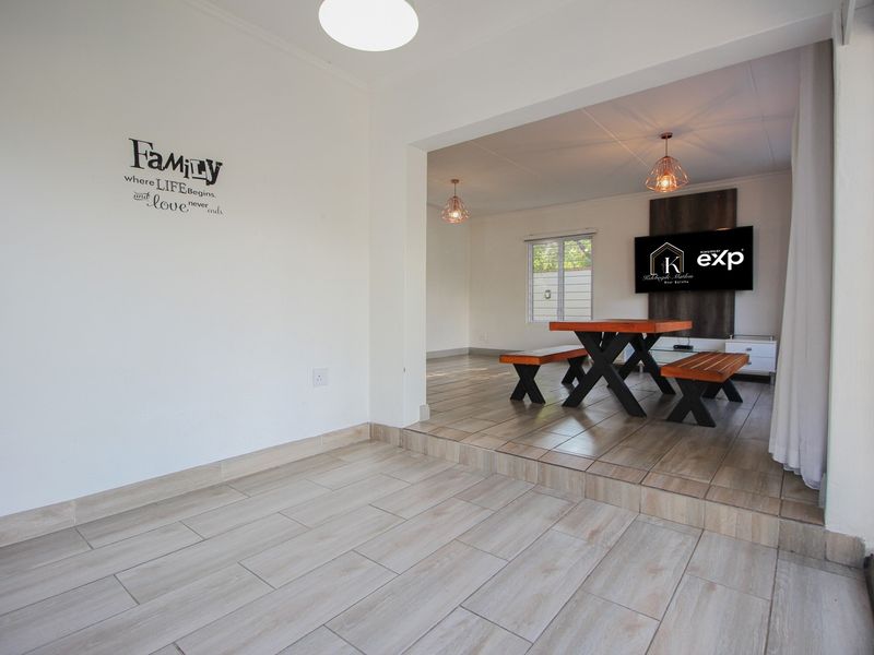 An open-plan living area featuring tiled flooring, a raised platform section, and modern pendant lighting, creating a versatile and connected space.