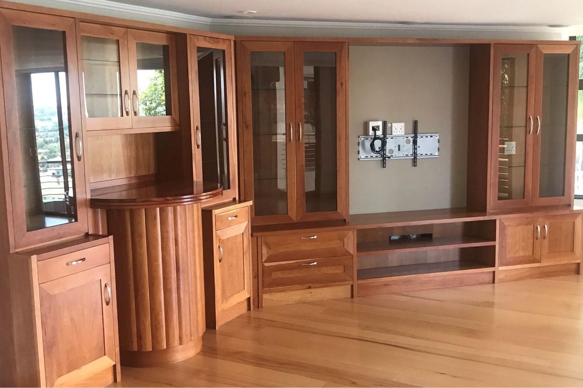 Spacious living area featuring extensive custom built-in wooden cabinetry with glass display units and polished hardwood flooring.
