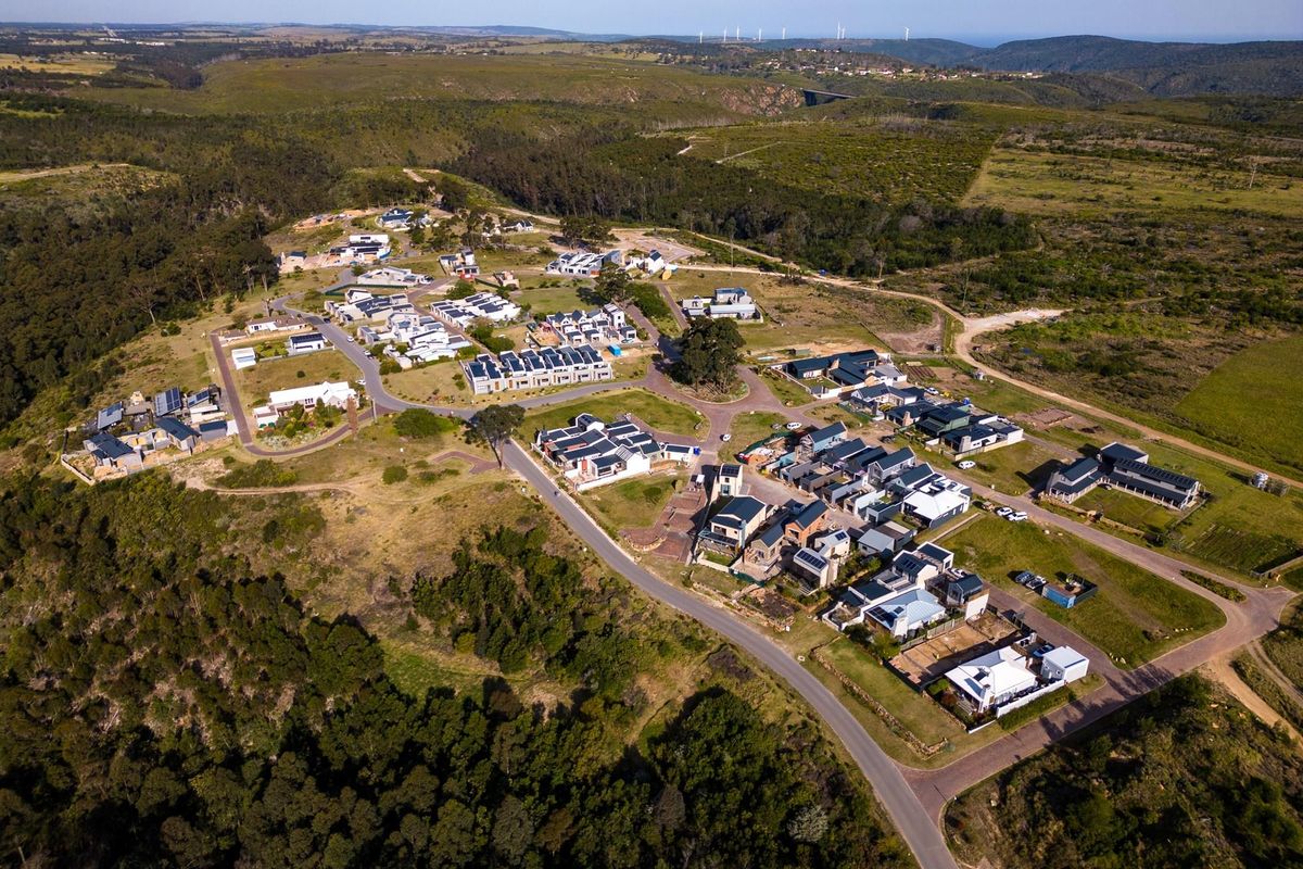Aerial view of a residential estate development featuring modern homes with solar panels, set within a scenic, hilly landscape.