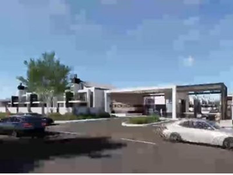 A modern residential estate entrance featuring contemporary architectural design, paved access roads, and landscaped surroundings.