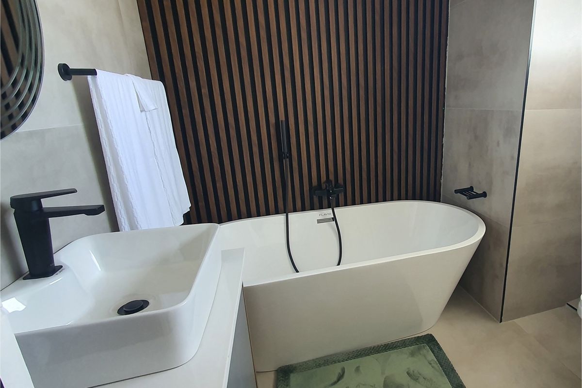 Modern bathroom featuring a freestanding bathtub, matte black fixtures, and a decorative timber slat feature wall.