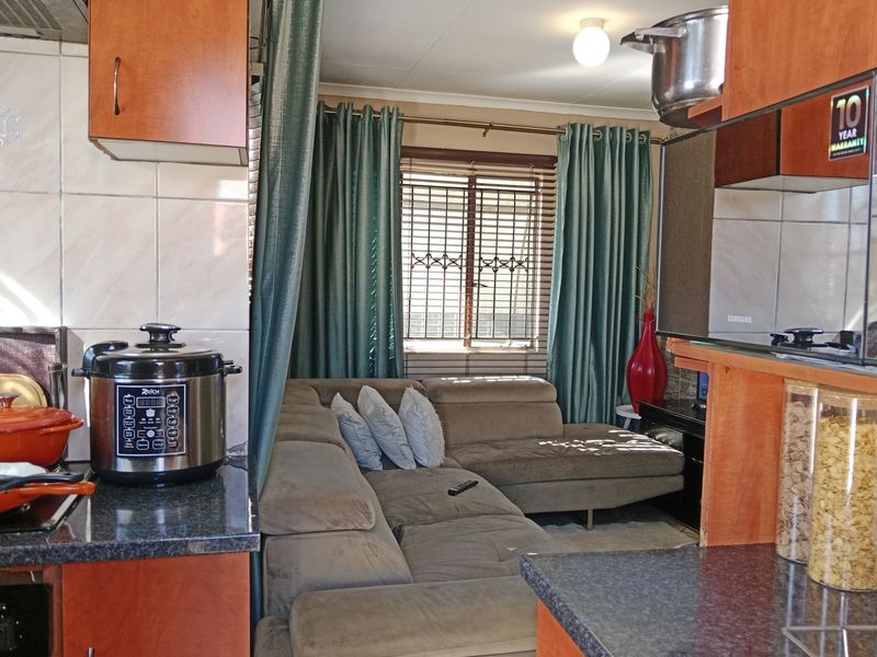 Open plan kitchen and living area featuring built-in cabinetry, granite countertops, and security bars on the window.
