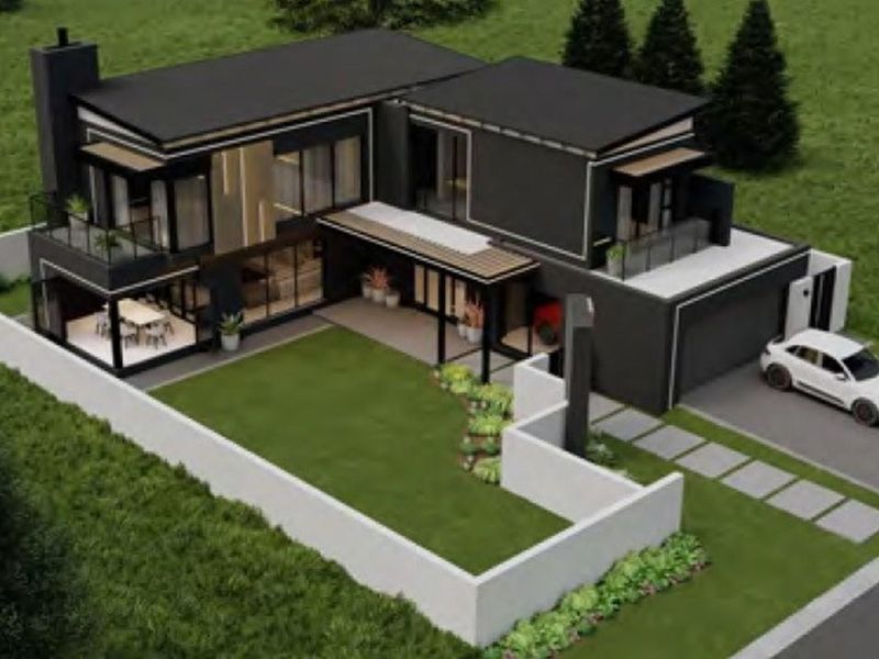 An aerial view of a modern double-storey house featuring a flat roof, balcony, patio, and a private garden with a paved driveway.