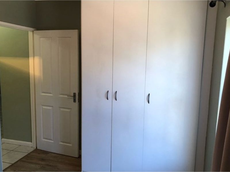 A bedroom interior featuring built-in white cabinetry and a doorway leading to an adjacent tiled space.