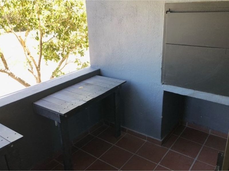 A covered balcony featuring a built-in braai and tiled flooring, offering a functional outdoor space for entertaining.
