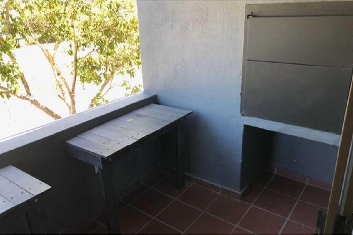 A covered balcony featuring a built-in braai and tiled flooring, offering a functional outdoor space for entertaining.