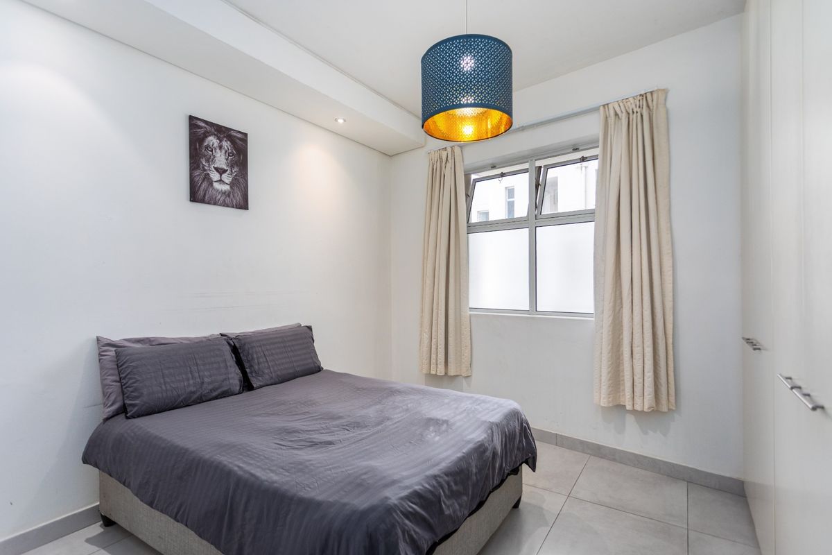 A well-maintained bedroom featuring tiled flooring, built-in cupboards, and a window with curtain tracks.