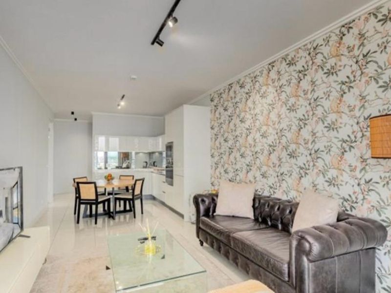 Modern open-plan living and dining area featuring a sleek kitchen, tiled floors, and a decorative wallpaper feature wall.
