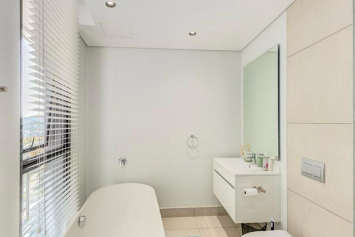 Modern bathroom featuring a sleek freestanding bathtub, wall-mounted vanity, large mirror, and neutral tiling, offering a clean and contemporary aesthetic.