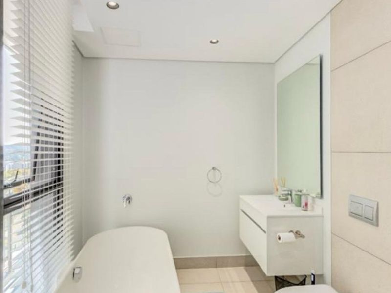 Modern bathroom featuring a sleek freestanding bathtub, wall-mounted vanity, large mirror, and neutral tiling, offering a clean and contemporary aesthetic.