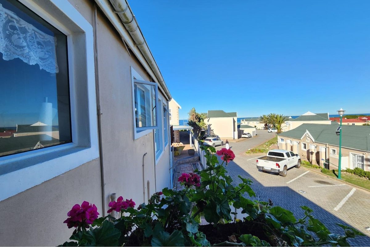 Exterior view from an elevated position overlooking the apartment complex grounds, parking area, and surrounding residential neighborhood.