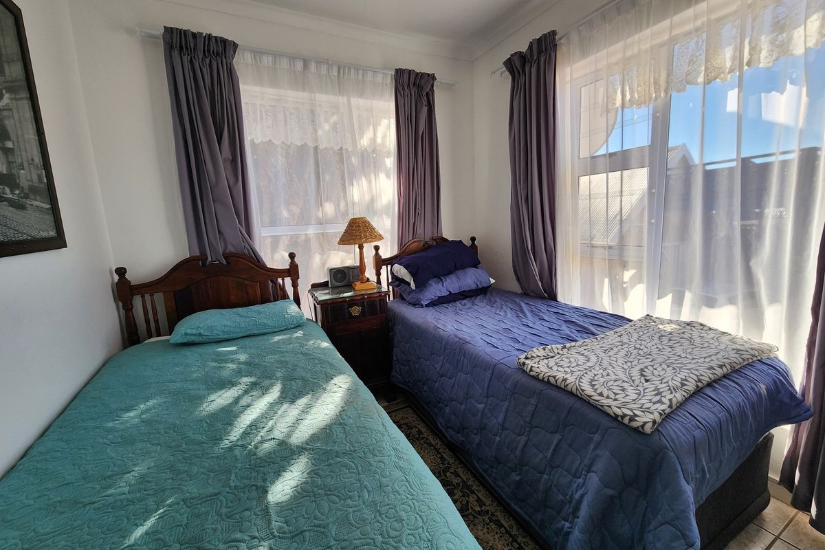 A bright bedroom featuring dual windows with curtains, providing natural light and a view of the exterior.