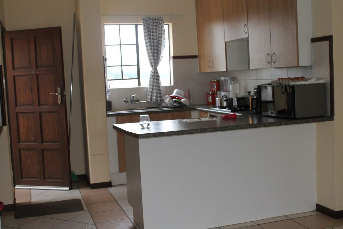 A functional kitchen featuring wooden cabinetry, a breakfast counter, tiled flooring, and a window above the sink area.