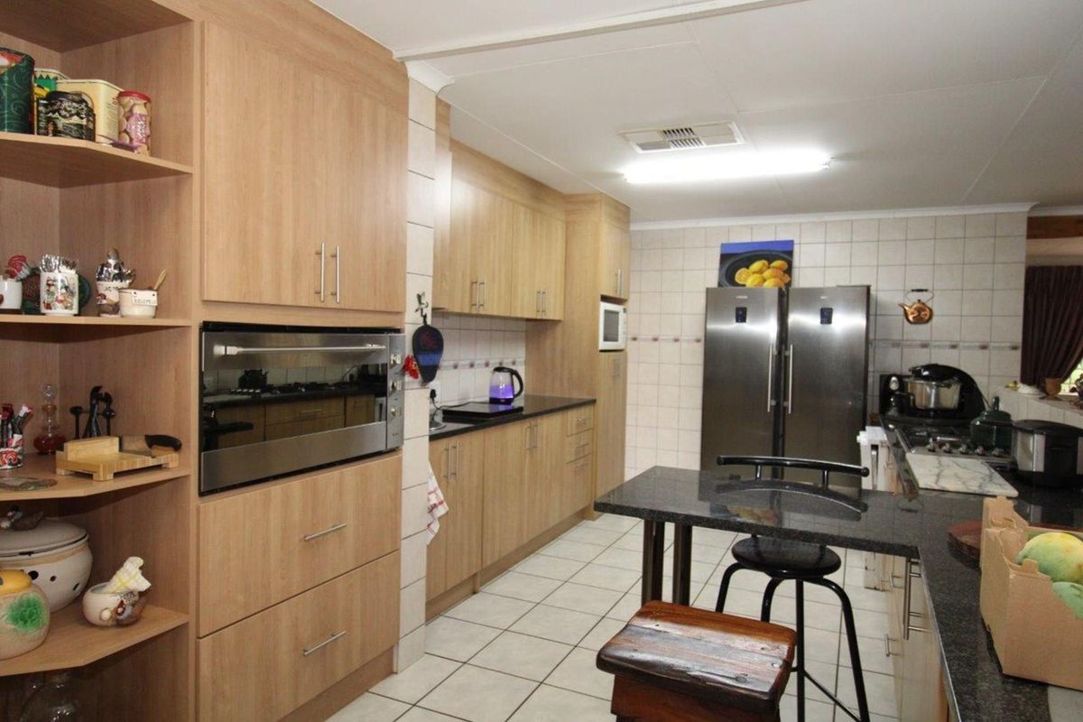 A functional kitchen featuring light wood cabinetry, granite countertops, tiled flooring, and built-in oven and microwave units.