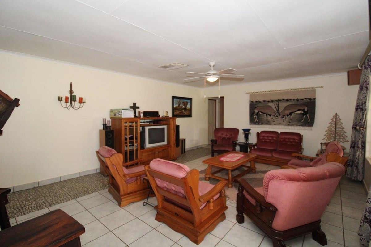 A spacious living room featuring tiled flooring, a ceiling fan, and neutral wall finishes, providing a comfortable and functional area for relaxation.