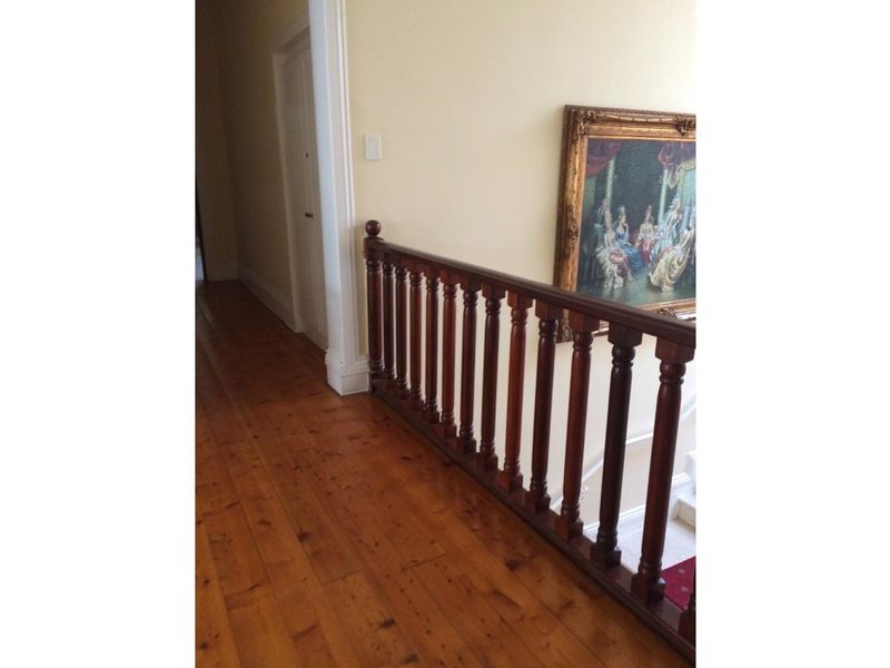 A hallway featuring polished timber flooring and a traditional wooden balustrade overlooking the lower level.