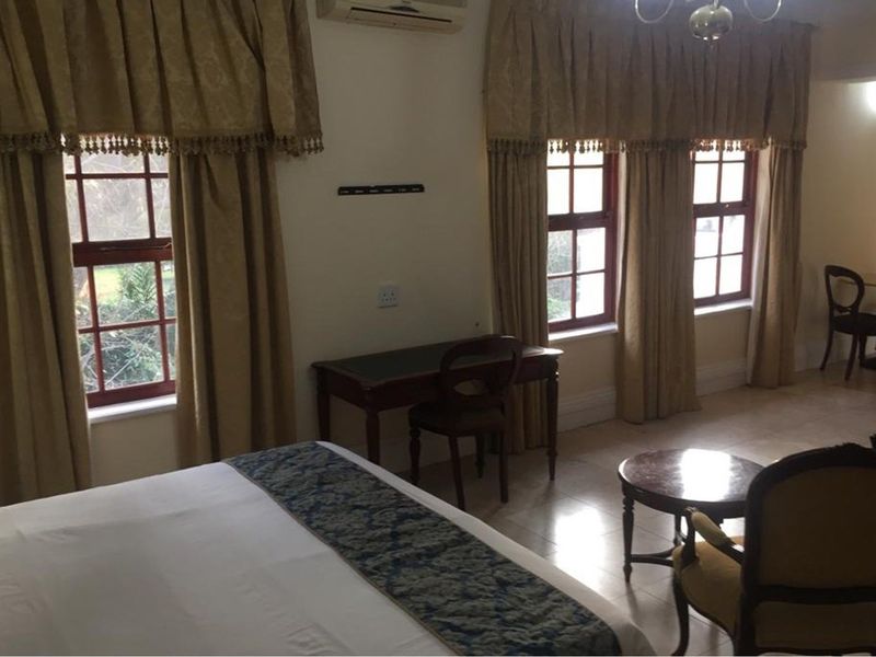 A spacious bedroom featuring tiled flooring, multiple windows with traditional frames, and a wall-mounted air conditioning unit.