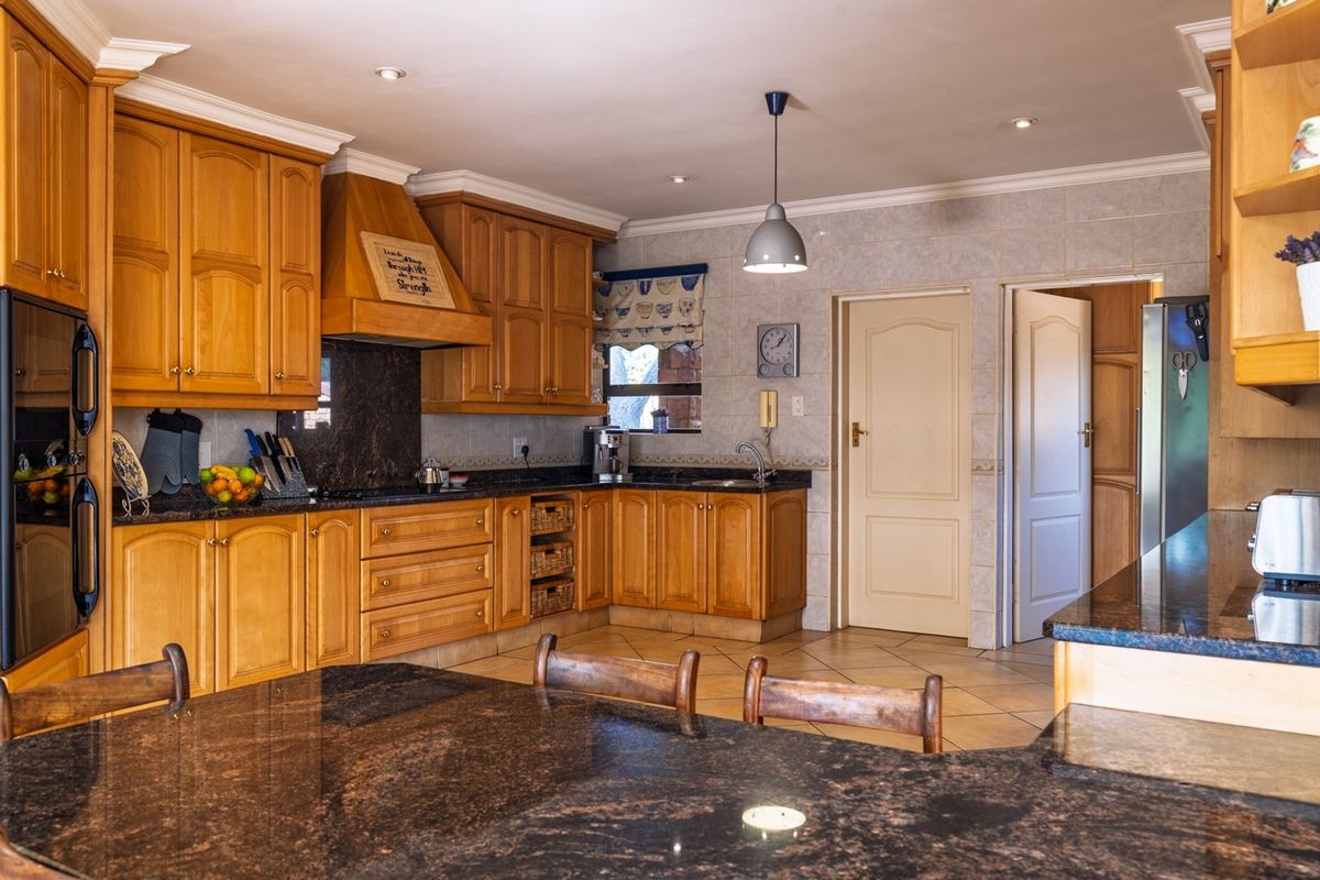 A traditional kitchen featuring solid wood cabinetry, dark granite countertops, tiled splashbacks, and recessed ceiling lighting.