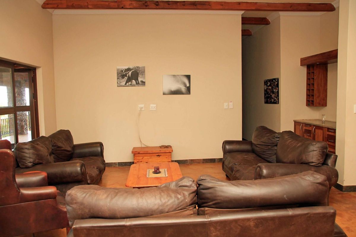 Spacious living area featuring exposed timber ceiling beams, tiled flooring, and a built-in wooden bar unit.