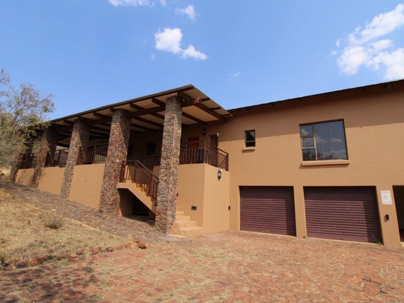 Exterior view of a multi-level house featuring a stone-pillared covered patio, double garage, and paved driveway.