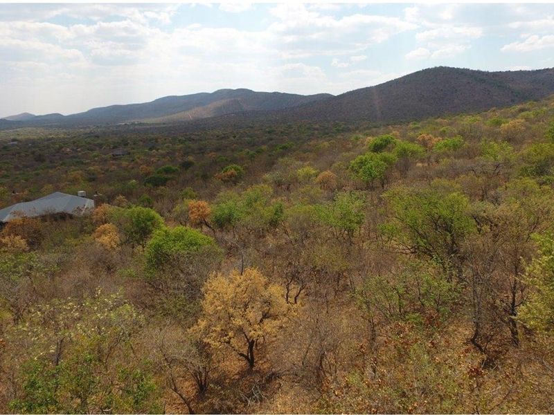 An elevated aerial view showcasing the expansive natural landscape, surrounding bushveld, and distant mountain ranges.