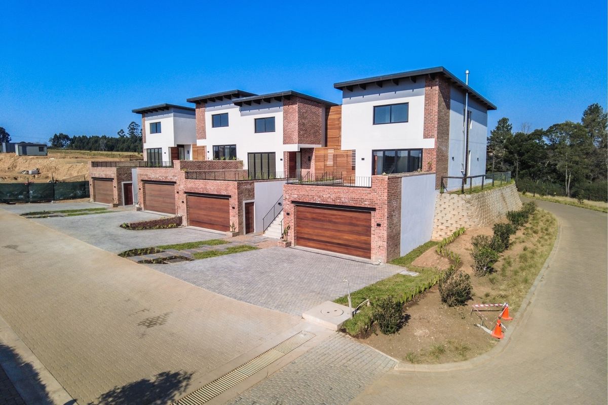 Aerial view of a modern townhouse complex featuring brick and plaster facades, paved driveways, and integrated garages.
