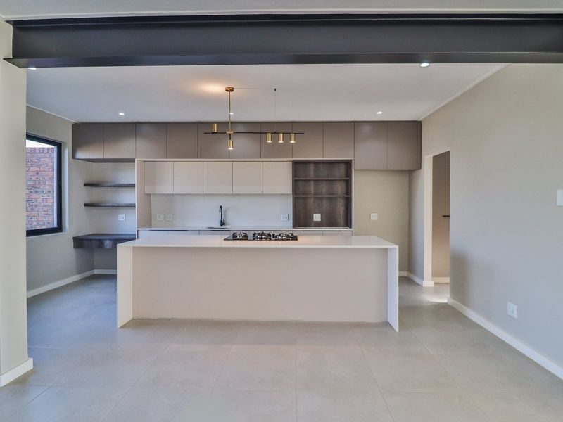 Modern open-plan kitchen featuring a central island with a built-in gas hob, sleek cabinetry, and contemporary pendant lighting.