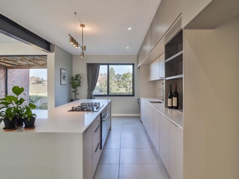 Modern open-plan kitchen featuring a large central island with integrated gas hob, sleek cabinetry, and seamless flow to the outdoor patio area.