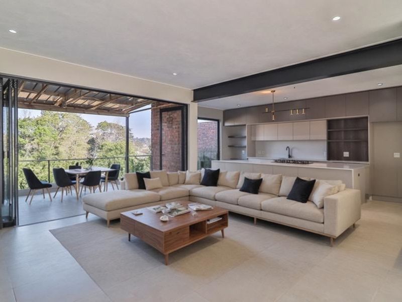 Modern open-plan living area featuring a sleek kitchen with integrated cabinetry and seamless flow to a covered balcony with scenic views.