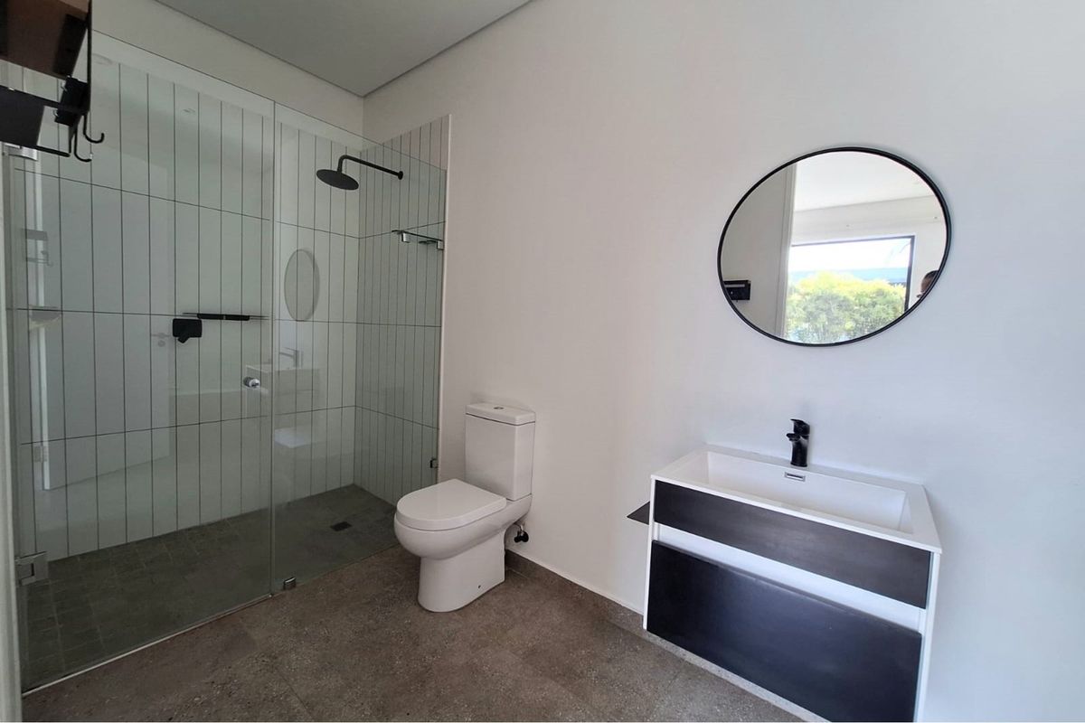 Modern bathroom featuring a walk-in glass shower, wall-mounted vanity with basin, and a contemporary toilet.
