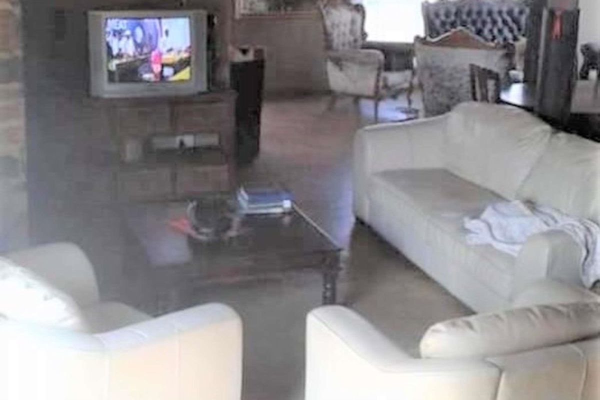 A living room area featuring tiled flooring and a brick fireplace structure.