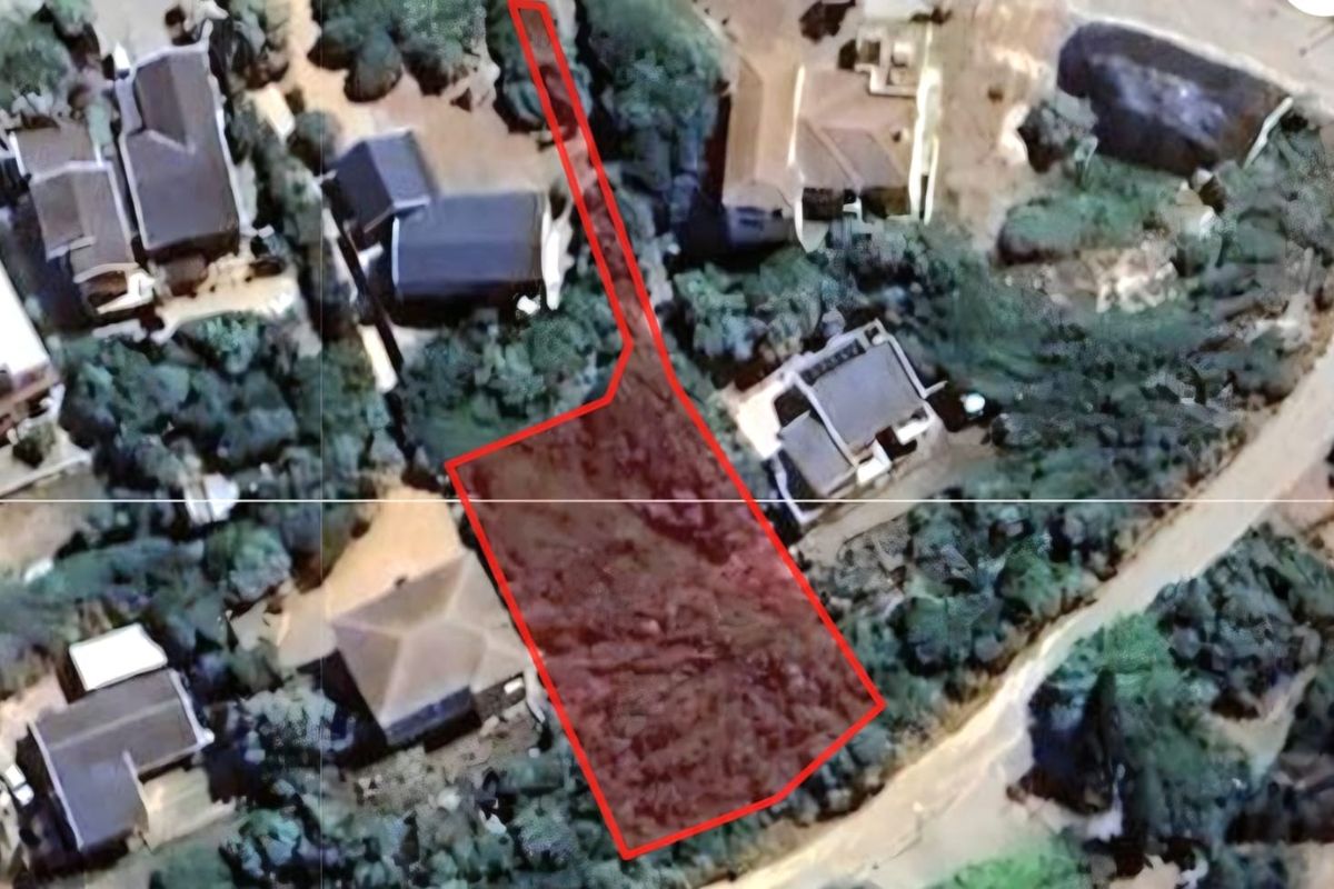 An aerial view showing the boundaries of a vacant residential land plot situated within an established neighborhood.