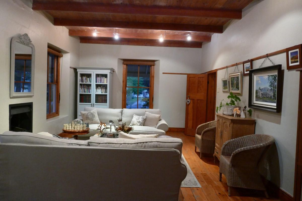 A cozy living room featuring exposed timber ceiling beams, polished wooden flooring, and a built-in fireplace, creating a warm and inviting atmosphere.