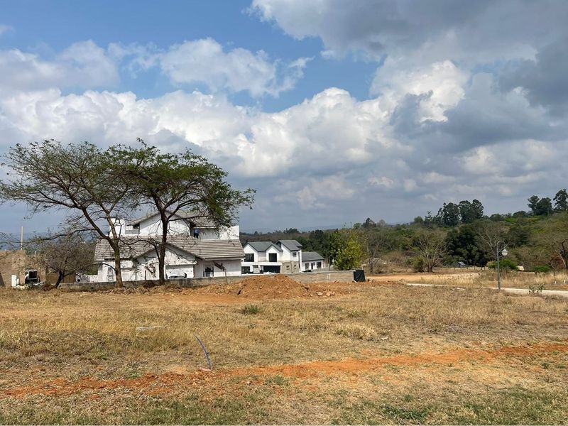 A view of a residential development site featuring partially constructed houses and undeveloped surrounding land.