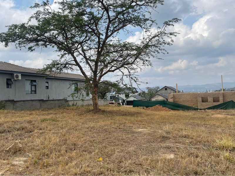 A view of the property grounds showing the adjacent residential structure and surrounding landscape with a large mature tree.