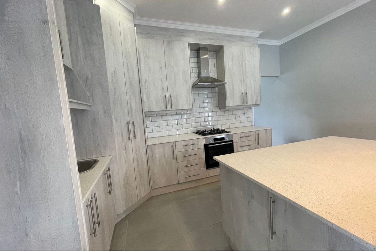 Modern kitchen featuring light wood-grain cabinetry, stone countertops, a central island, built-in oven, gas hob, and a classic subway tile backsplash.