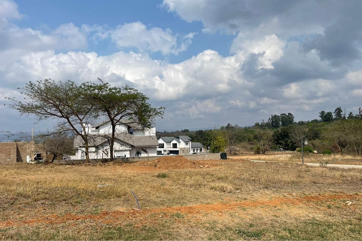 A view of a residential development site featuring partially constructed houses and undeveloped surrounding land.