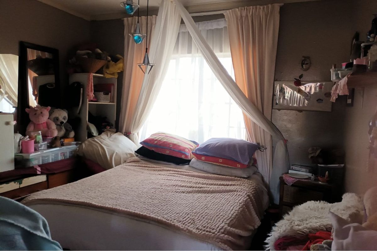 A bedroom featuring a window with draped curtains, providing natural light to the space.