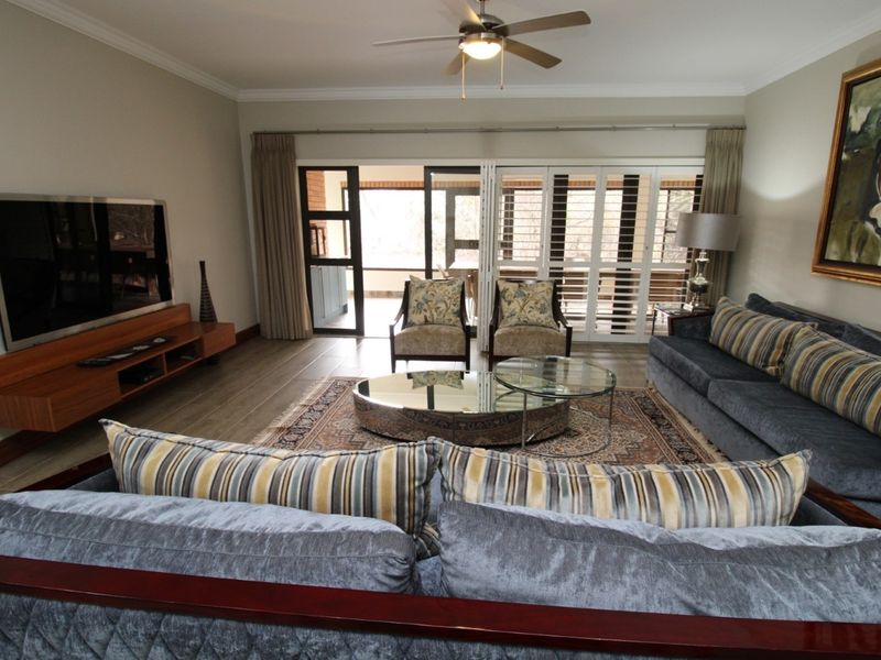 Spacious living room featuring tiled flooring, crown molding, a ceiling fan, and large sliding doors providing access to an outdoor patio area.