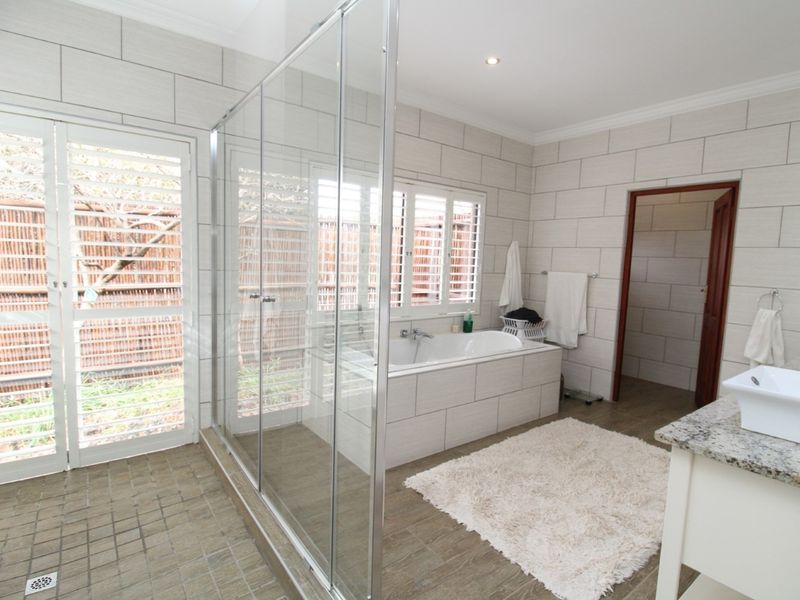 Modern bathroom featuring a large walk-in glass shower, a built-in bathtub, tiled walls, and a vanity with a vessel sink.