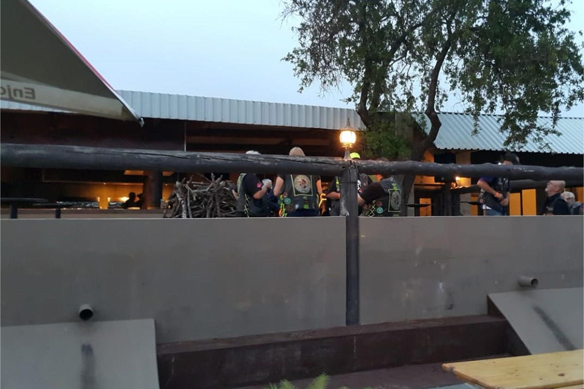 A covered outdoor patio area featuring a corrugated metal roof and timber railing, suitable for social gatherings.
