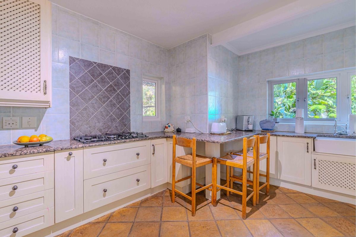 A functional kitchen featuring granite countertops, a built-in gas hob, farmhouse-style sink, and tiled flooring with a breakfast nook area.