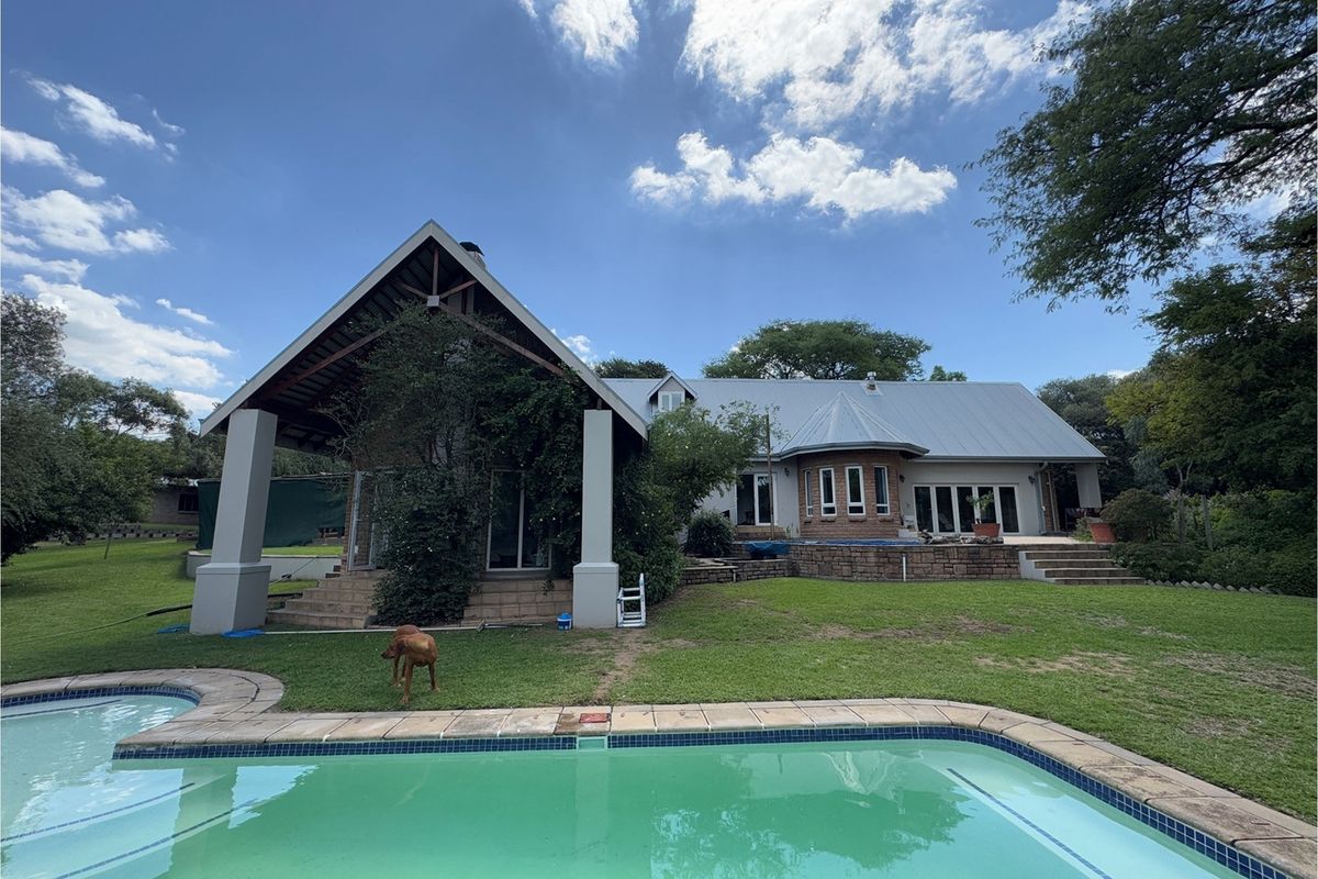 Rear view of the property featuring a large covered patio, swimming pool, and landscaped garden area with a metal roof structure.