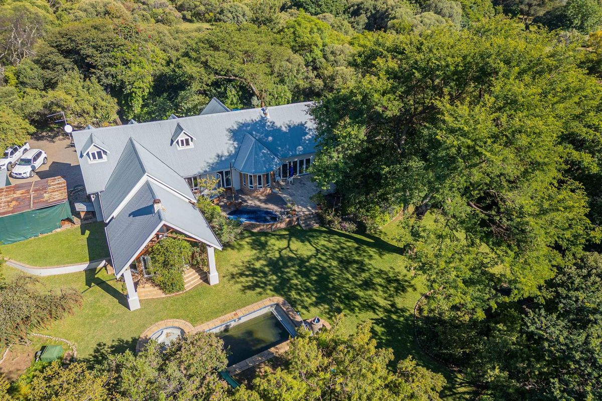 Aerial view of a small holding property featuring a large residence, expansive garden, swimming pool, and mature trees in a tranquil setting.