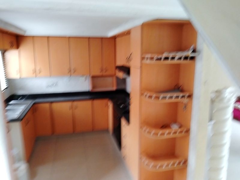 A dated kitchen featuring laminate cabinetry, stone countertops, and built-in appliances, offering a functional layout ready for modernization.