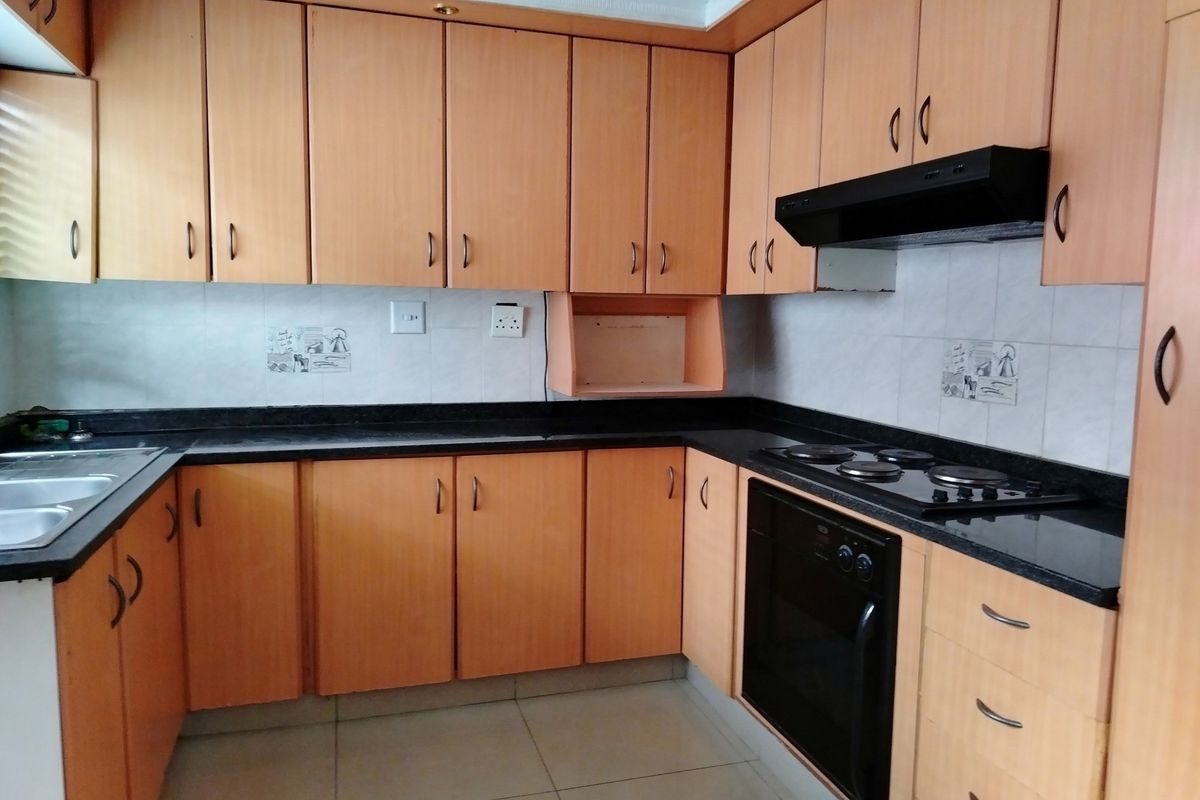 Functional kitchen featuring laminate cabinetry, granite countertops, built-in oven, electric hob, and extractor fan with a tiled backsplash.