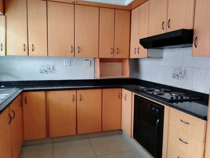 Functional kitchen featuring laminate cabinetry, granite countertops, built-in oven, electric hob, and extractor fan with a tiled backsplash.